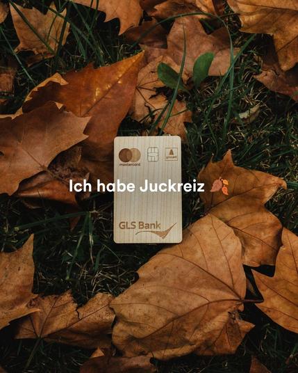 GLS Bank Holzkarte die im Laub liegt. Aufschrift: Ich habe Juckreiz 🍂