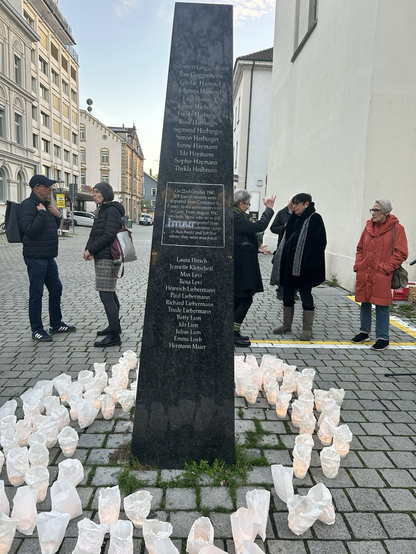 Menschen versammeln sich um die schwarze Gedenkstele für die Deportierten nach Gurs in Konstanz.