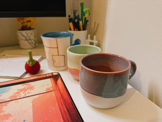 Drei benutzte Tassen und eine Tasse als Stifthalter