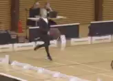 a woman in a suit is holding a basketball on a court in front of a crowd
