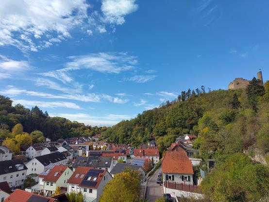 Blick in ein Tal mit Burg auf einem Berg bei leichter Bewölkung und blauem Himmel