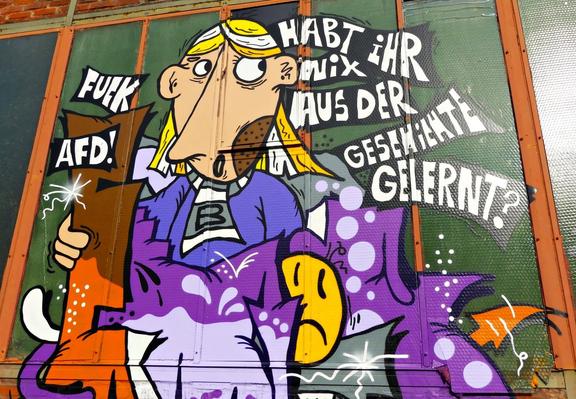 Graffiti mit einer Comicfigur, die ein Schild mit der Aufschrift 'FUCK AFD!' hält, und dem Text 'HABT IHR MIX AUS DER GESCHICHTE GELERNT?'