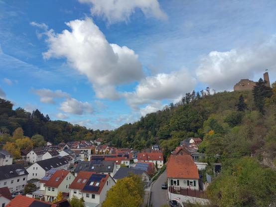 Blick in ein Tal mit Burg auf einem Berg bei leichter Bewölkung