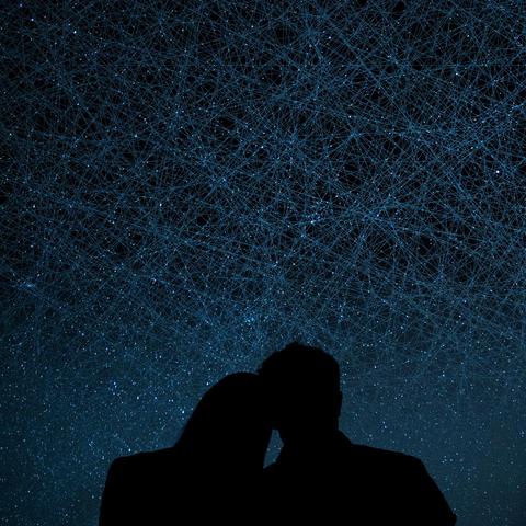 Schwarze Silhouette eines Liebespaares, von hinten gezeigt. Über den Köpfen der beiden ein endloser dunkelblauer Nachthimmel; die zahlreichen funkelnden Sterne werden jedoch überlagert von einem dichtmaschigen Netz feiner, einander chaotisch überkreuzender gerader Linien, welche die Flugbahnen tausender Satelliten am Firmament darstellen. (no AI)