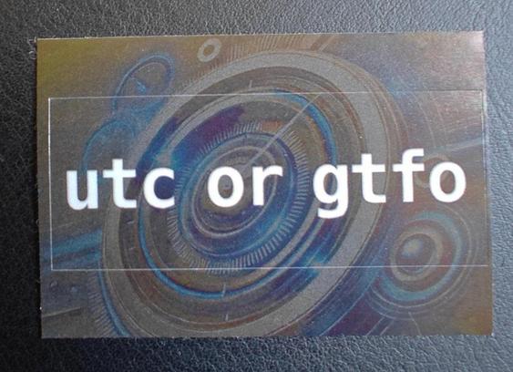 A sticker with a spiral galaxy motif in shades of blue, purple, and pink. The sticker is circular and features the text "utc or gtfo" in white lowercase letters.