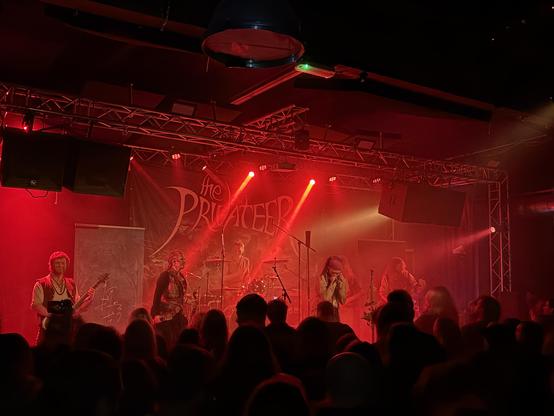 Six piece band The Privateer on stage at Artik Freiburg, lit up in red