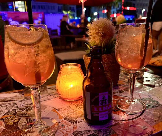 Wir sitzen in unserem Lieblingslokal Sommersalon auf der Reeperbahn. Und auf dem Tisch stehen Sati und Astra Bier (mit dem St Pauli Logo 1. Liga)